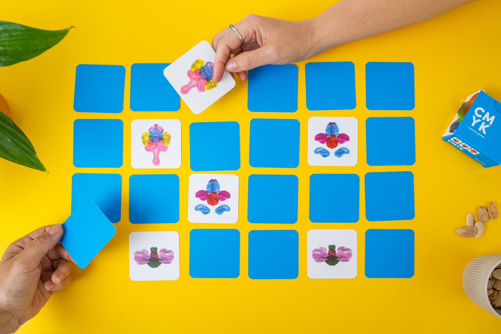 abstract memory game. Hands playing a matching game with colorful cards on a yellow background